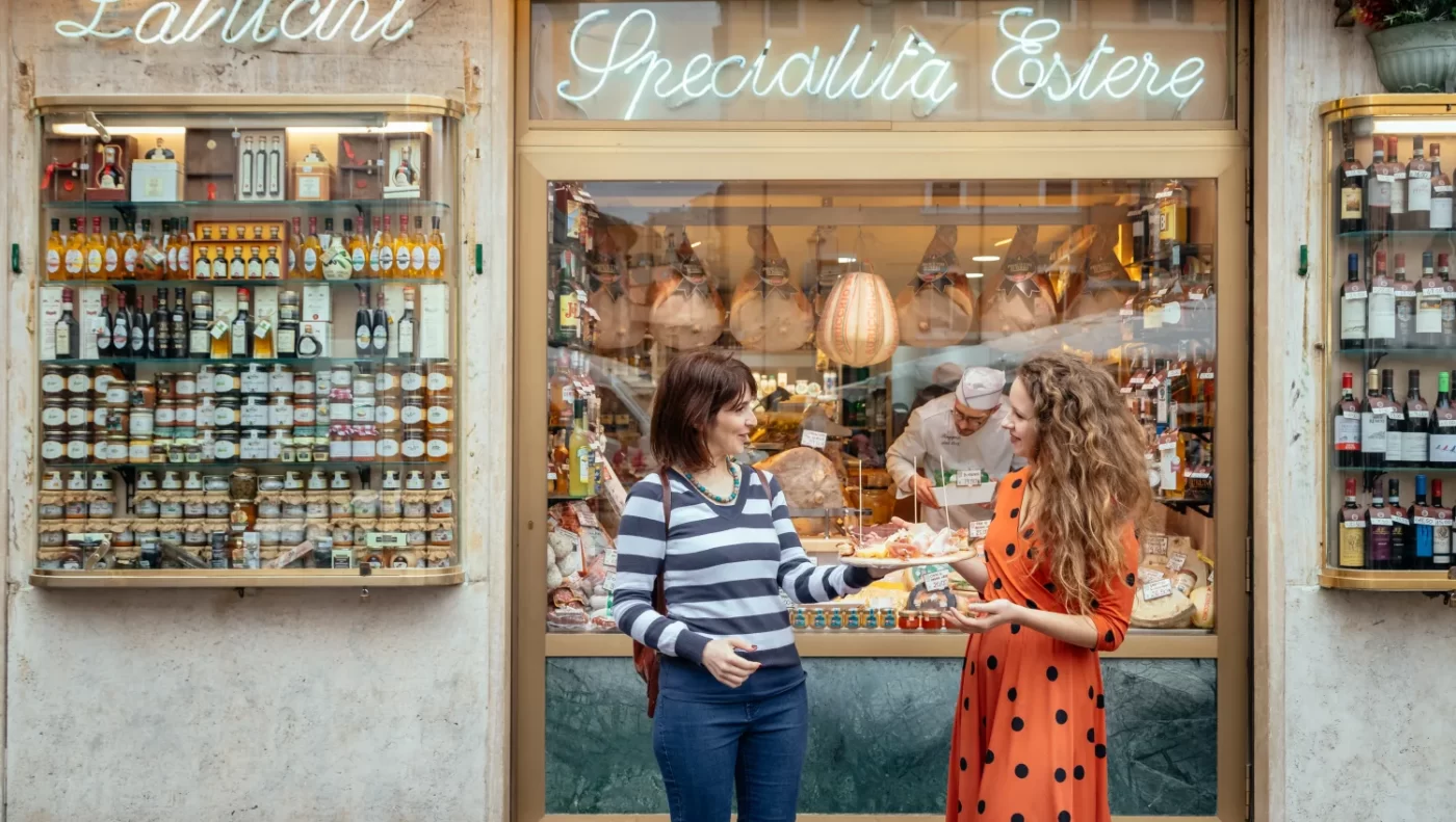Two women trying food outside a shop in Rome