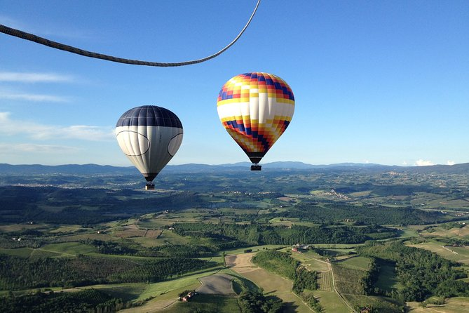 2 colorful hot air balloons flying above tuscany