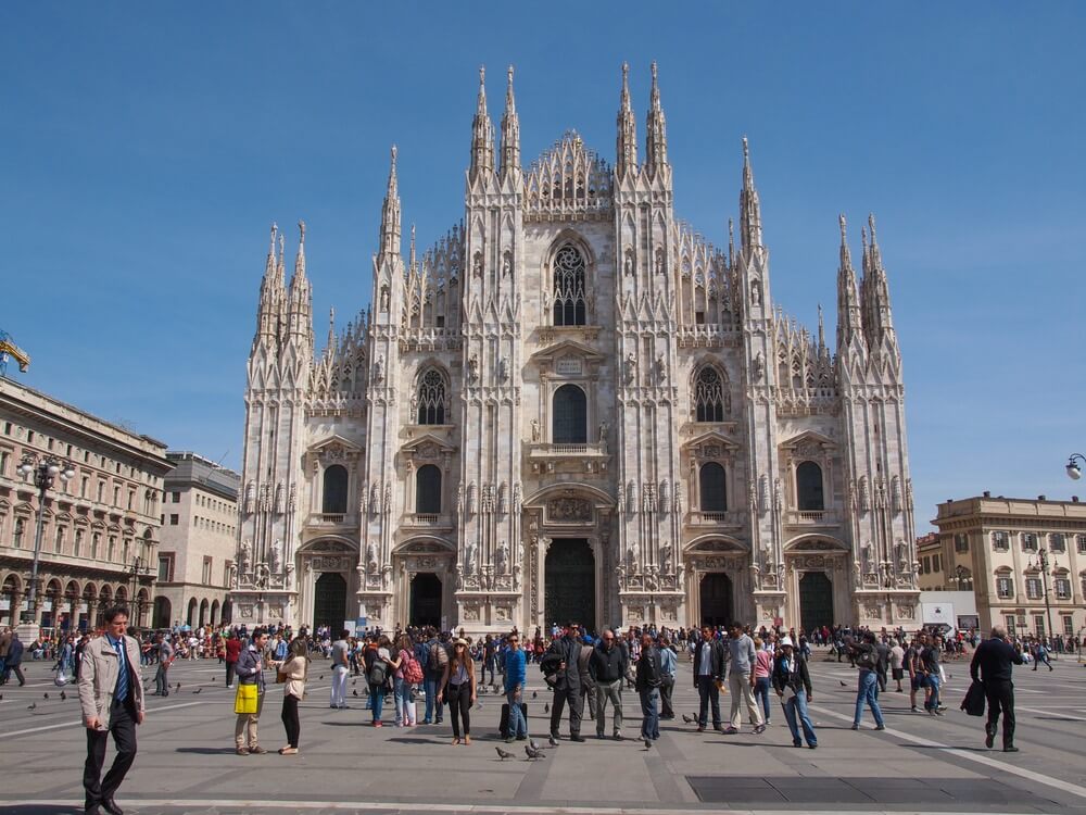 The cathedral in Milan with people in front of it.
